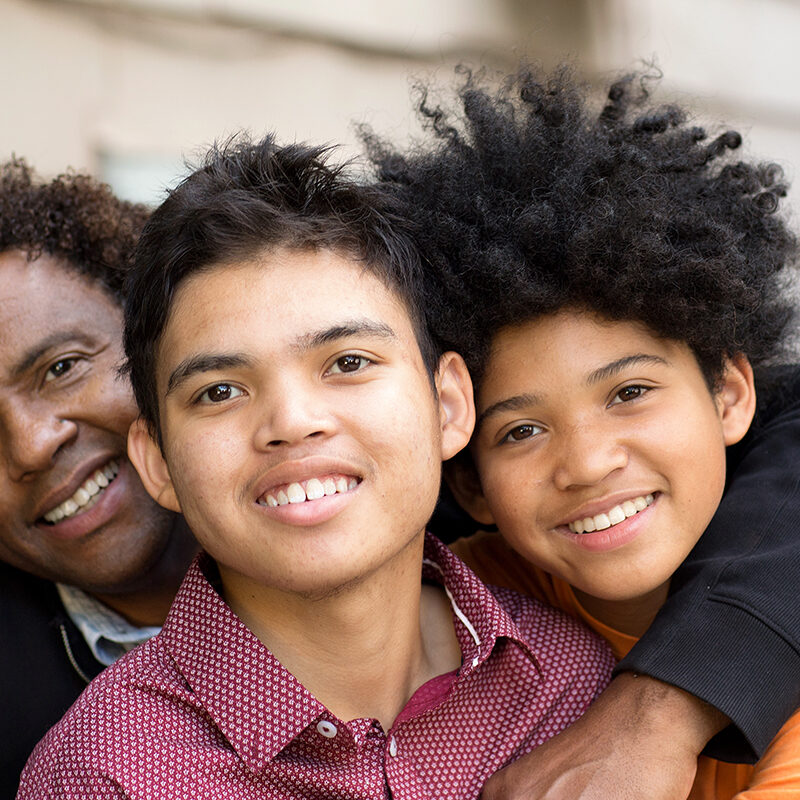 African American father hugging his two sons.